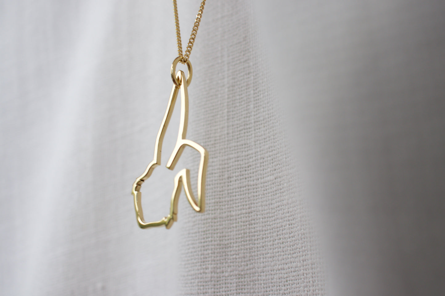 Gold necklace with a unique design on a plain background