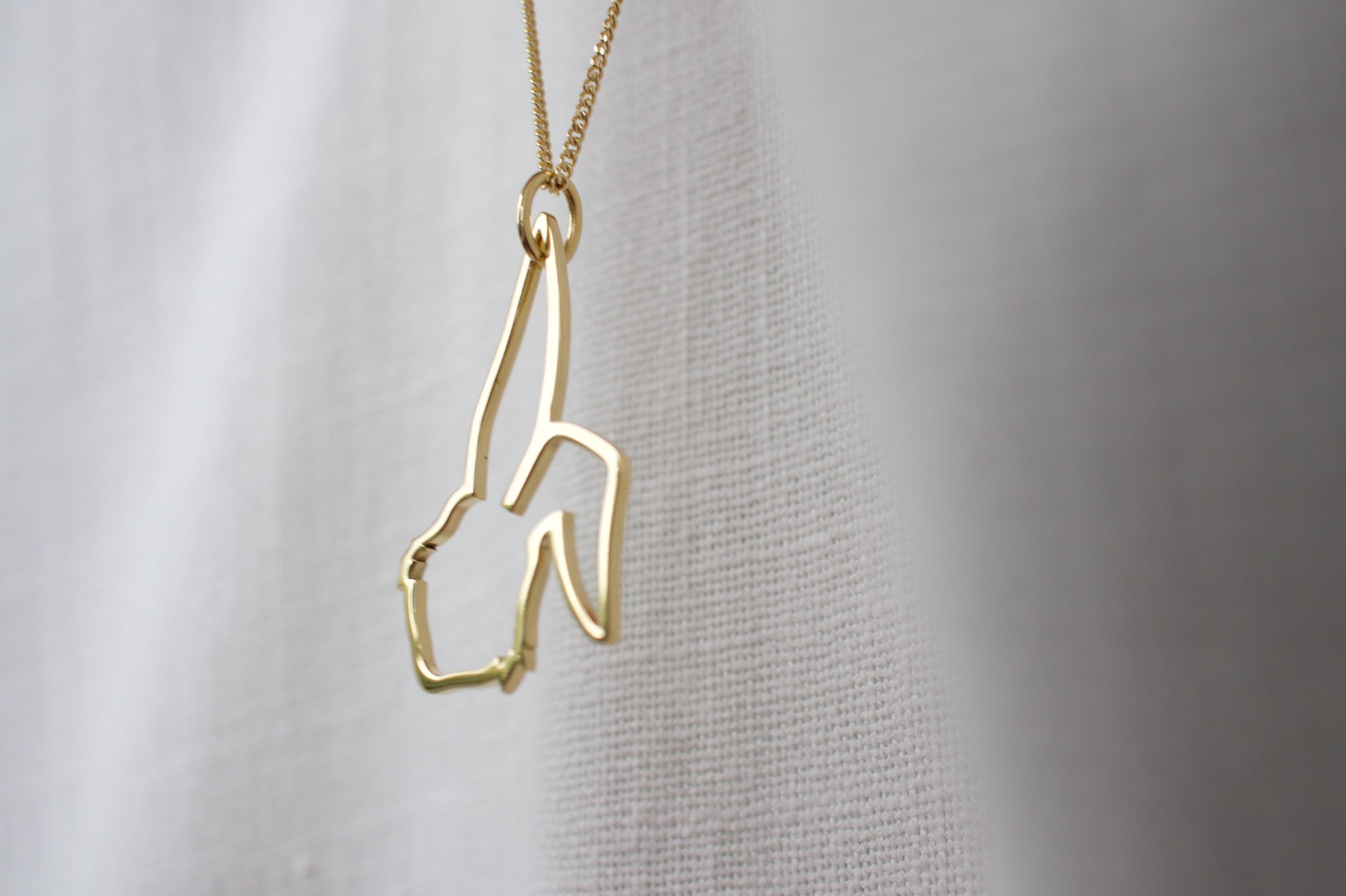 Gold necklace with a unique design on a plain background